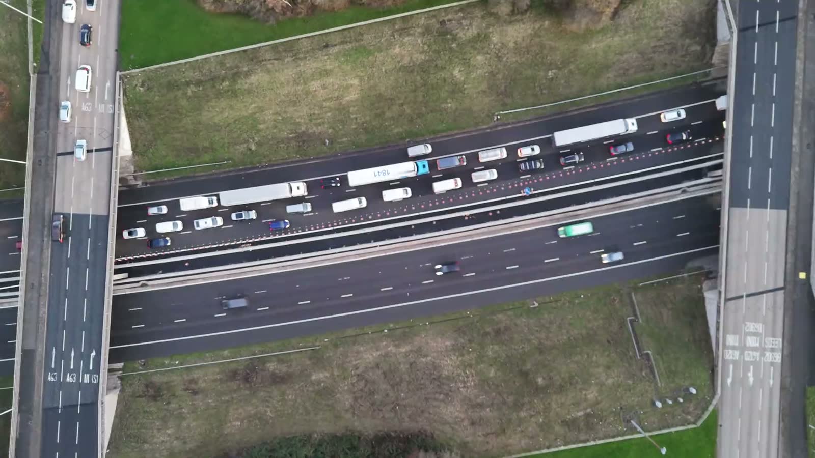Trucks and vans on a motorway, seen from above.